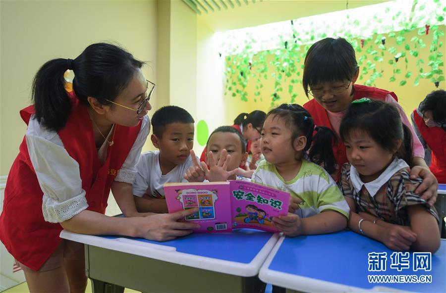 7月9日，在杭州市临安区一幼儿园的暑托班，锦城街道胜利社区的青年社工向小朋友们讲解安全知识绘本。新华社记者 徐昱 摄
