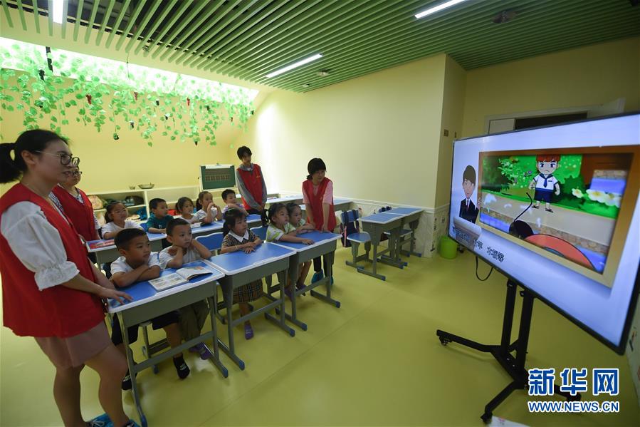 7月9日，在杭州市临安区一幼儿园的暑托班，锦城街道胜利社区的青年社工陪小朋友们观看安全教育视频。新华社记者 徐昱 摄