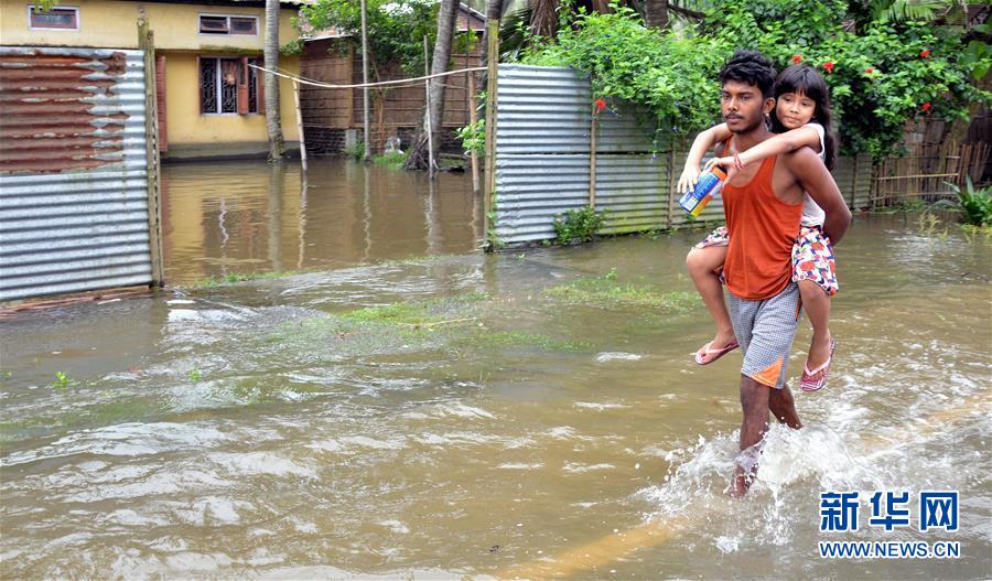 7月13日，在印度阿萨姆邦卡姆鲁普，行人涉水前行。 近日，印度东北部阿萨姆邦遭遇暴雨引发的洪涝灾害。 新华社发
