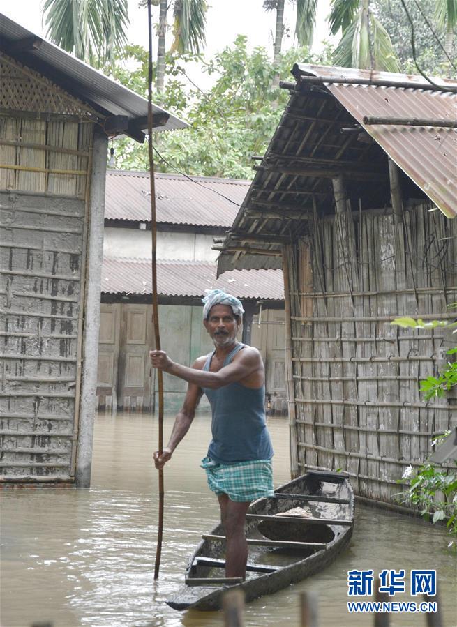 7月13日，在印度阿萨姆邦卡姆鲁普，一名男子划船离开积水围困的房屋。 近日，印度东北部阿萨姆邦遭遇暴雨引发的洪涝灾害。 新华社发
