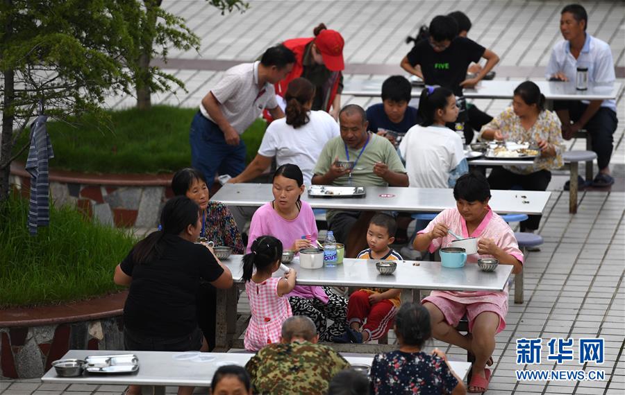 7月14日，在宿松县洲头乡中心小学集中安置点，洲头乡泗洲村的村民在吃晚餐。 近日，安徽省宿松县洲头乡泗洲村的300多名村民因洪水被转移到该乡中心小学集中安置点。安置点工作人员、志愿者利用学校食堂为村民们烹饪饭菜，让村民们在安置点吃上热腾腾的三餐。 新华社记者 刘军喜 摄