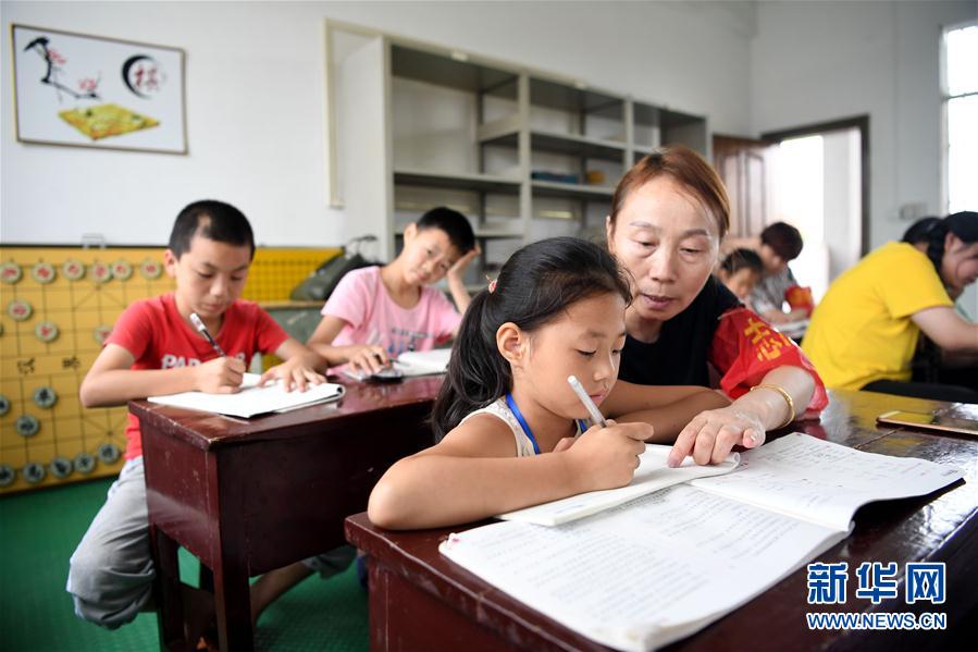 7月16日，在安徽省宿松县洲头乡中心小学集中安置点，教师志愿者辅导孩子们完成暑假作业。近日，安徽省宿松县洲头乡泗洲村的300多名村民因洪水被转移到洲头乡中心小学集中安置点，这些村民中包括约30名儿童。学校开放运动场所供孩子们使用，并安排教师志愿者辅导孩子们的暑期作业。 新华社记者 刘军喜 摄