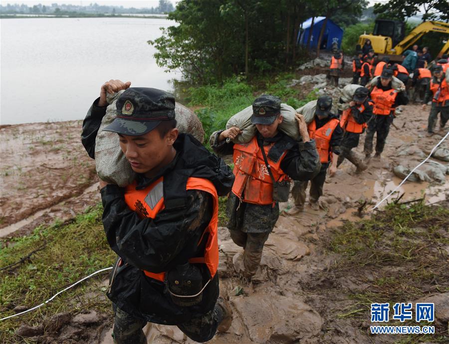 7月18日，在位于安徽省和县黄坝村的石跋河堤坝上，武警安徽总队马鞍山支队的官兵在搬运沙袋。 新华社记者 周牧 摄