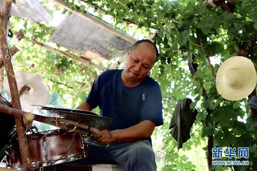 张宏远在位于新疆玛纳斯县的自家院落里维修自制的架子鼓（7月14日摄）。新华社记者 孙哲 摄