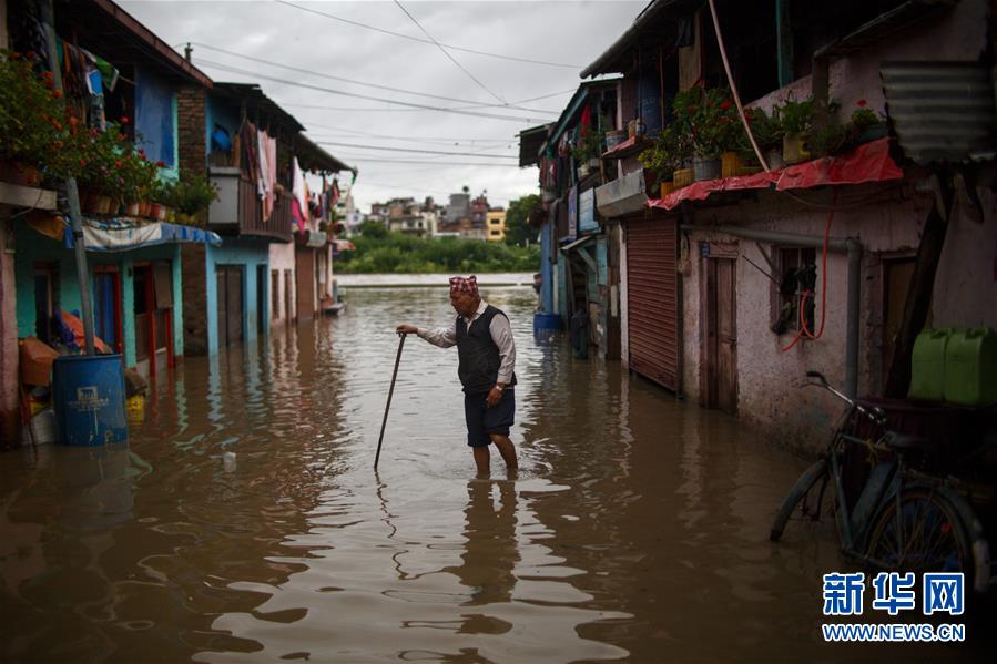 7月20日，尼泊尔首都加德满都一名居民在积水中行走。 受季风强降雨影响，巴格马蒂河河水上涨，导致尼泊尔首都加德满都部分地区出现内涝。 新华社发（苏拉韦·什雷斯塔 摄）