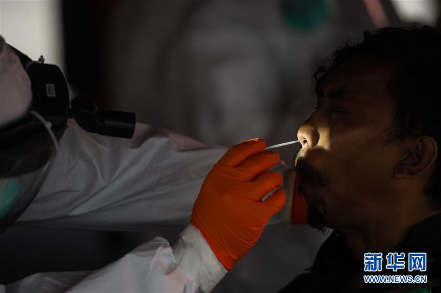 7月21日，一名医务人员为印度尼西亚南唐格朗的居民进行新冠病毒检测采样。 印尼国家抗灾署21日发布的新冠疫情数据显示，该国确诊病例比前一天增加1655例，累计确诊89869例；累计死亡4320例；累计治愈48466例。 新华社发（维里摄）