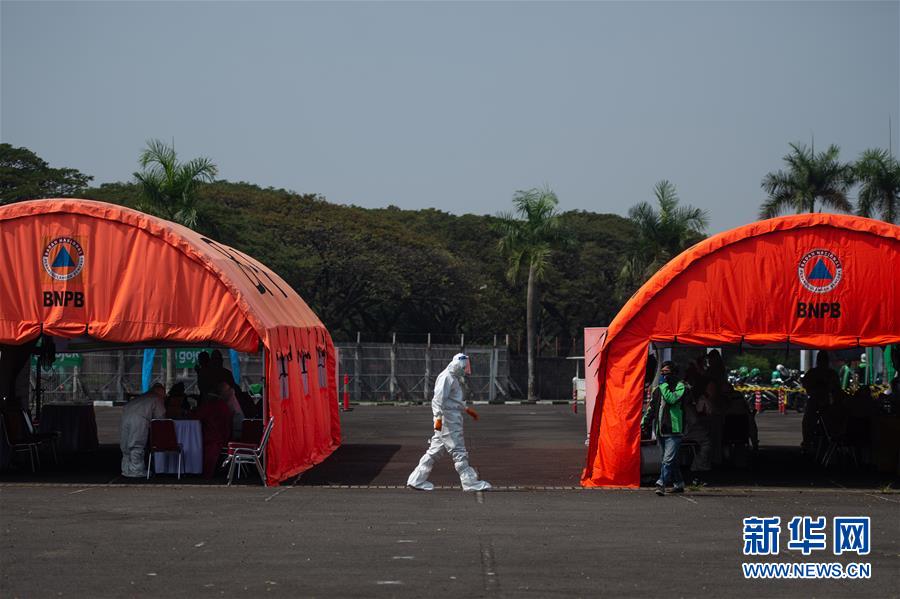 7月21日，一名医务人员为印度尼西亚南唐格朗的居民进行新冠病毒检测采样。 印尼国家抗灾署21日发布的新冠疫情数据显示，该国确诊病例比前一天增加1655例，累计确诊89869例；累计死亡4320例；累计治愈48466例。 新华社发（维里摄）