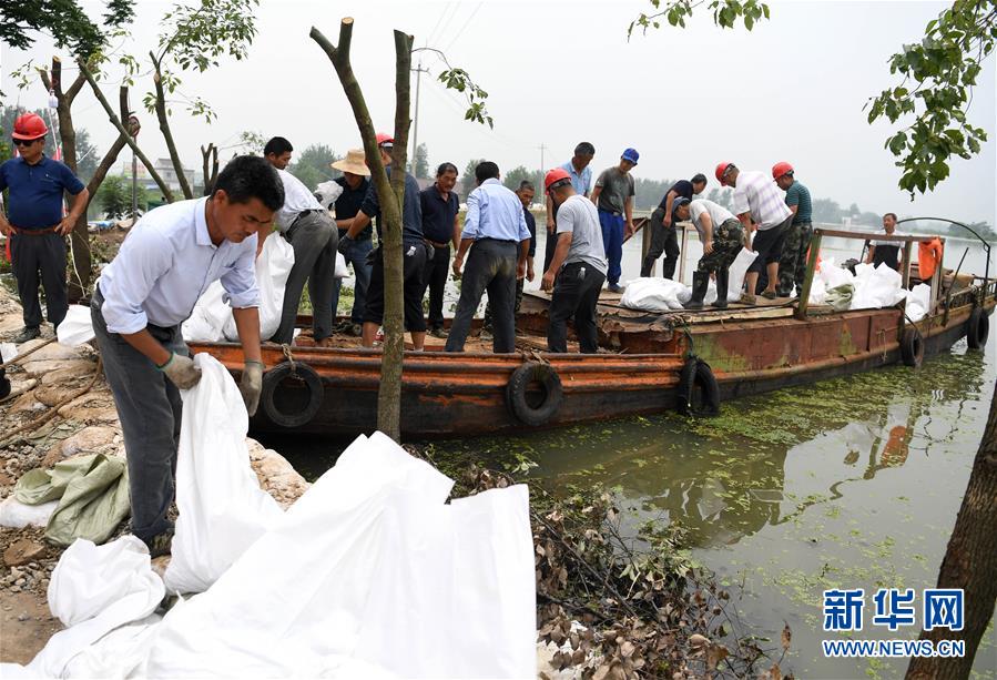 7月21日，在和县乌江镇石跋河新圩段，救援人员在装运抢险物资。 受洪水影响，安徽省和县乌江镇石跋河新圩段出现100多米的堤坝滑坡、塌方险情。因出现险情一侧堤坝无道路可通行，抢险所用的砂石、木料等物资需要从石跋河对岸“摆渡”过来。救援抢险人员携手“接力”转运抗洪物资，共同奋战2天，成功排除险情。 新华社记者 刘军喜 摄