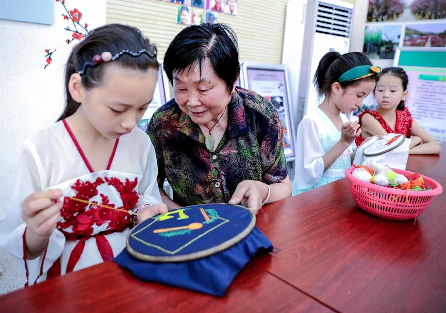 7月24日，在长兴县林城镇连心村，孩子们在传统手艺人的指导下学习刺绣。新华社记者 徐昱 摄