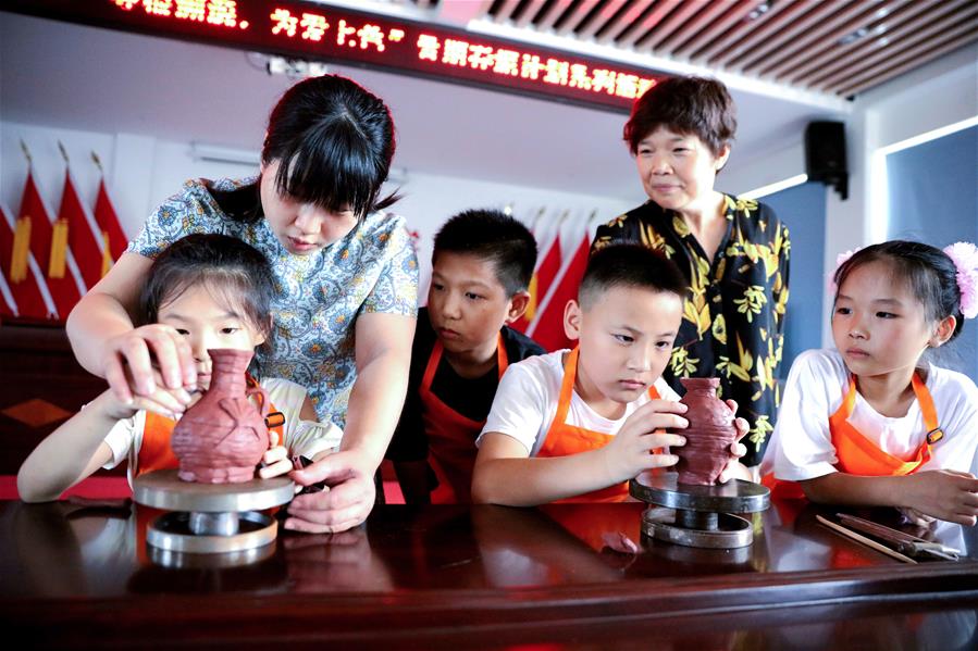7月24日，在长兴县林城镇方山窑村，孩子们在传统手艺人的指导下学习制作陶艺作品。新华社记者 徐昱 摄