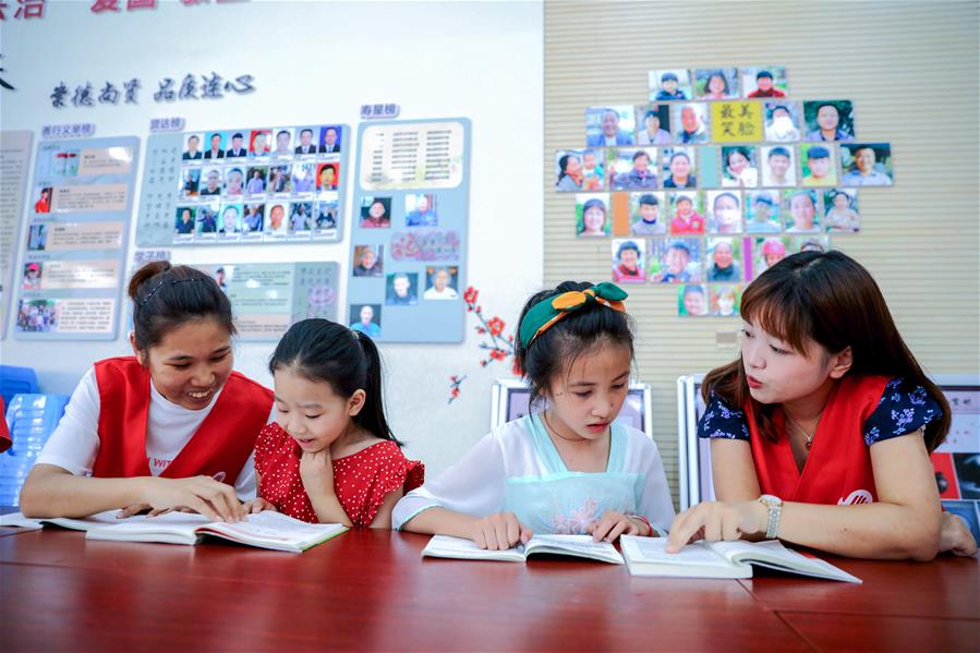 7月24日，在长兴县林城镇连心村，孩子们在大学生志愿者的指导下阅读课外书。近期，浙江省湖州市长兴县林城镇开展“春泥计划进乡村”暑期活动，当地的大学生、传统手艺人、非遗传承人等带领孩子们在暑期中参加做陶艺、刺绣等活动，丰富孩子们的暑期生活。 新华社记者 徐昱 摄