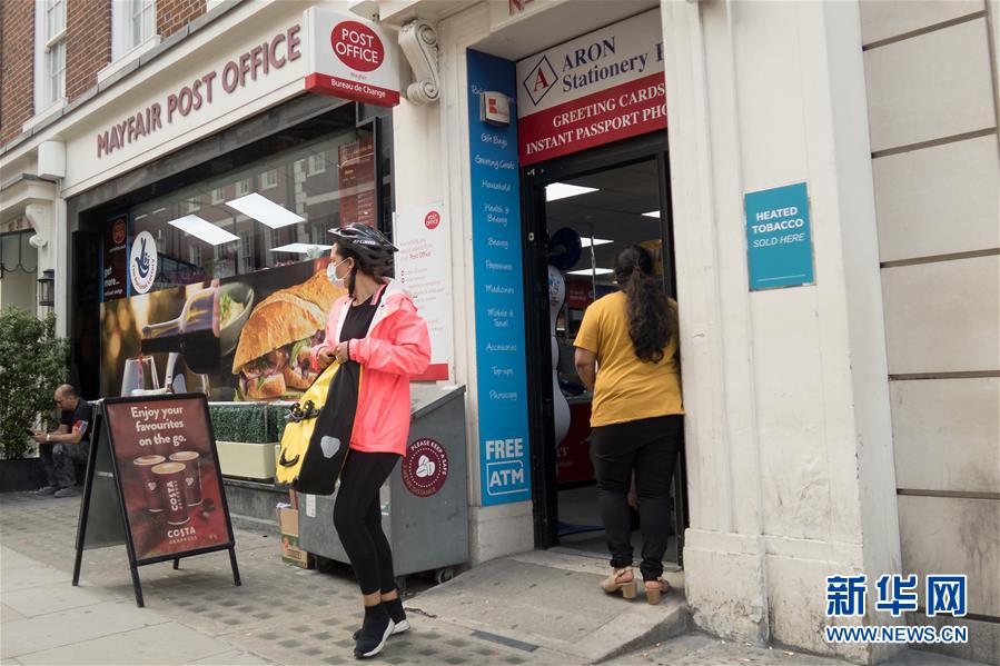 7月24日，一名戴口罩的顾客从英国伦敦一家邮局走出。 新华社发（蒂姆·爱尔兰摄）