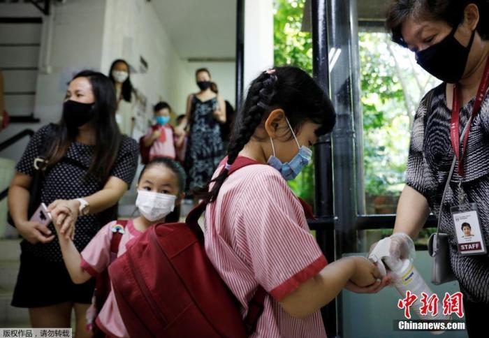 只有一些特定人群仍可获准戴面罩,包括难以长时间戴着口罩的12岁及以下孩童,以及因健康状况不适合长时间戴口罩,否则或会引起呼吸困难或其他症状的人。在教室或讲座场合面向人群授课者,若主要站在同个位置发言,并且能与其他人保持安全距离,也可继续戴面罩。图为当地时间6月2日,新加坡校重新开学,幼儿园学生进教室前用洗手液消毒。 点击进入下一页