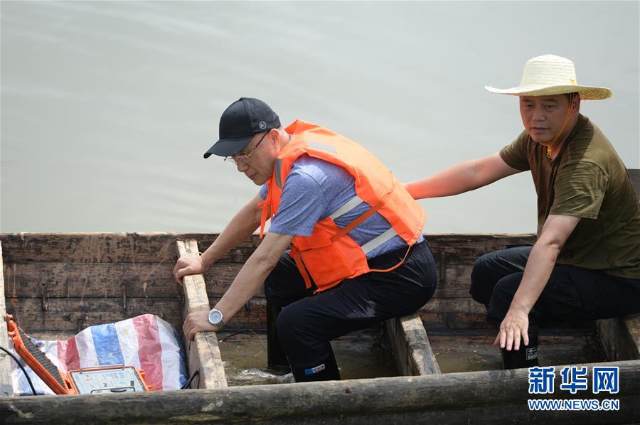 7月28日，在临湘市聂市镇毛湾垸，何继善（左）查看检测仪使用情况。新华社发（陈振海摄）