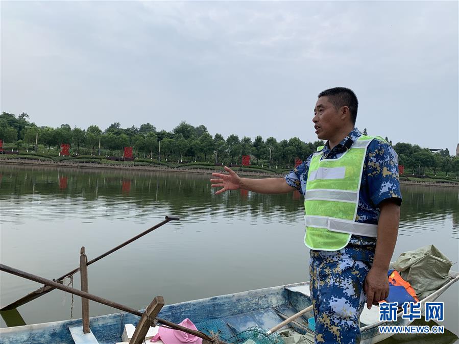 李代国在龙溪河畔准备登船清漂（7月25日摄）。新华社记者 周闻韬 摄