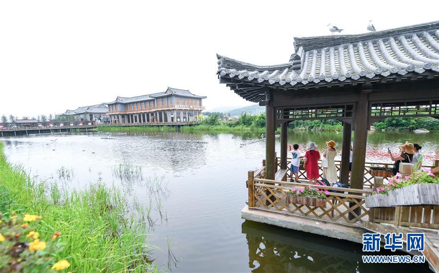 8月1日，游客在珲春市敬信镇防川村的湖边欣赏景色。 吉林省延边朝鲜族自治州珲春市敬信镇防川村位于中、俄、朝三国交界处，被誉为“东方第一村”。近年来，防川村利用民俗风情资源和乡土文化，发展民宿旅游、农家乐等，推动农业和旅游业融合发展，打造特色乡村旅游品牌，吸引了众多游客前来。 新华社发（颜麟蕴 摄）