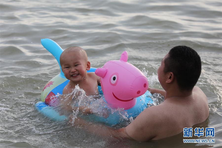 8月2日，家长带着孩子在江苏省淮安市洪泽区渔人湾浴场游玩。 新华社发（万震 摄）