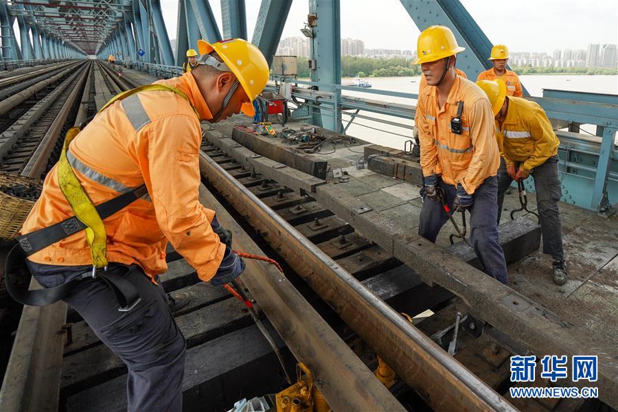 8月6日，桥隧工郭继浩（左二）和工友在南京长江大桥作业点进行更换枕木作业。今年28岁的郭继浩和班组其他9名工友主要负责南京长江大桥铁路桥梁设备的日常巡查、养修和临时性抢修等工作。　　连日来，江苏省南京市持续高温天气，在中国铁路上海局集团有限公司南京桥工段南京大桥车间，近80名桥隧工不畏高温酷暑，坚守岗位，确保暑运列车的安全运行。戴着安全帽，穿着防护服，桥隧工们趁着没有列车运行的“天窗时间”，每天用脚步“丈量”大桥，保障长江大桥铁路桥运输畅通、安全。新华社记者 李博 摄