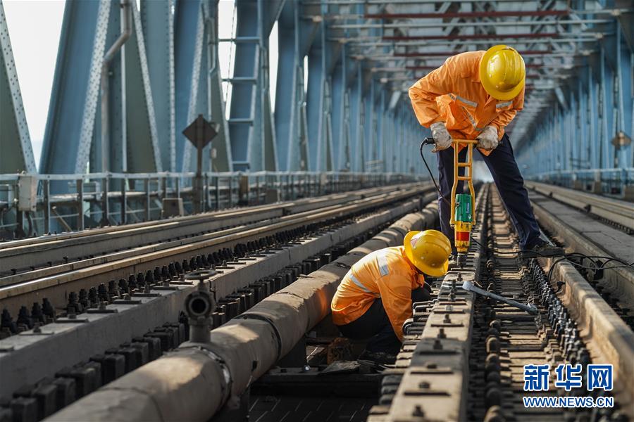 8月6日，两名桥隧工在南京长江大桥作业点拧紧螺帽，固定护木。新华社记者 李博 摄
