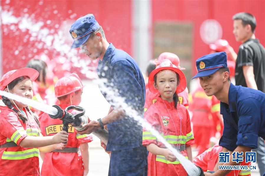 8月6日，消防员在毕节市消防救援支队碧阳大道特勤站带领学生体验消防水枪。 新华社发（陈曦 摄）