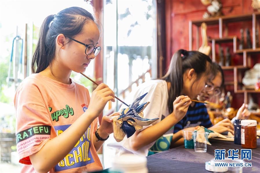 8月9日，贵州省安顺市第一高级中学的学生在安顺市傩雕文化博物馆为傩戏面具上色。新华社发（陈熙 摄）