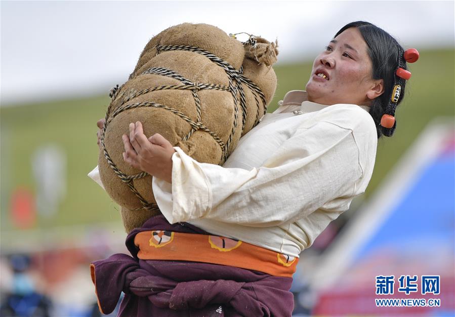 8月10日，一名妇女在参加抱石头比赛。当日，2020年那曲羌塘恰青格萨尔赛马艺术节在西藏那曲市格萨尔赛马场开幕，来自那曲各县区的农牧民在赛马场参加了抱石头比赛和押加赛。新华社记者 张汝锋 摄