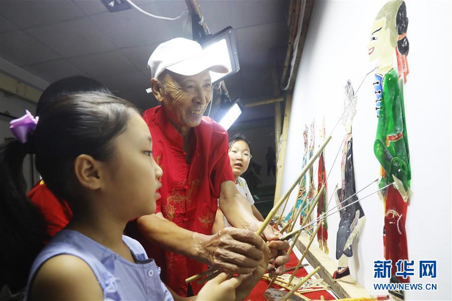 8月14日，皮影戏艺人在河北省唐山市丰润区文化馆指导小朋友表演皮影戏。 暑假期间，各地的孩子们通过丰富多彩的活动乐享假期、充实生活。 新华社发（朱大勇 摄）