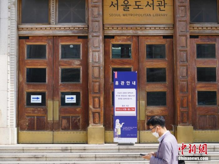 6月23日,一位韩国首尔市民经过首尔市立图书馆门前,该图书馆贴出闭馆通知。近来,包括韩国首尔、仁川、京畿道在内的首都圈确诊病例持续增加。<a target='_blank' href='http://www.chinanews.com/'>中新社</a>记者 曾鼐 摄 点击进入下一页