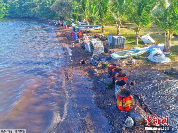 当地时间8月10日,志愿在在海边用油桶搜集泄露的原油。 点击进入下一页
