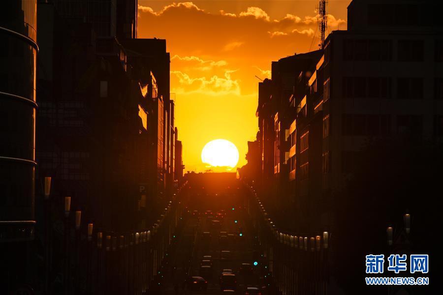 这是8月21日在比利时首都布鲁塞尔拍摄的落日景观。 当日，夕阳从布鲁塞尔法律大街上空缓缓下落，形成独特的落日景观。 新华社记者 张铖 摄