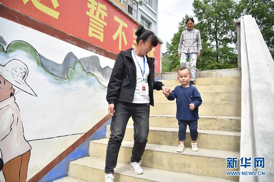 在贵州省毕节市纳雍县锅圈岩苗族彝族乡夹岩村，扶贫队员黄满陪儿子和婆婆在村委会散步（5月23日摄）。 新华社记者 骆飞 摄