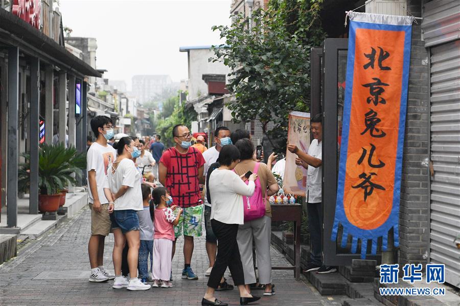 在北京杨梅竹斜街，游客在一家经营传统老北京手工艺品“兔儿爷”的小店参观（8月17日摄）。  新华社记者 鞠焕宗 摄