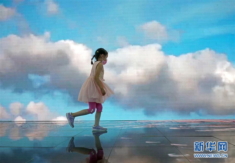 9月5日，在服贸会旅游服务专题展区内的世界旅游城市联合会展台，一名儿童走过播放着旅游宣传片的大屏幕。 该展台设有墙面和地面两块超大屏幕，循环播放着多个旅游宣传片，站在屏幕上仿佛置身于美景之中。 2020年中国国际服务贸易交易会于9月4日至9日在北京举行。 新华社记者 才扬 摄
