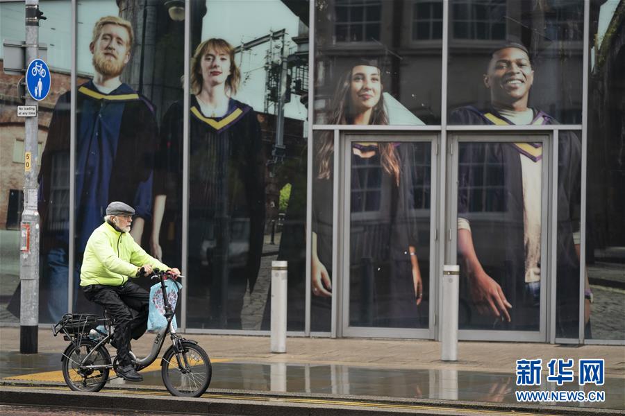 9月8日，一名男子骑自行车经过英国曼彻斯特大学。 英国各地近期陆续开学以来，每日新增感染病例数迅速上升，多所学校出现小规模集中感染。为遏制疫情蔓延，大曼彻斯特地区实行更加严格的防疫措施。 新华社发（乔恩·休珀摄）