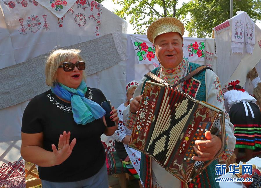 9月26日，在白俄罗斯首都明斯克郊区，一名女士与一名身着民族服装的乐手合影。 随着当地秋收的基本结束，白俄罗斯各地相继举办农业展销节等活动，欢庆秋收。 新华社发（任科夫摄）