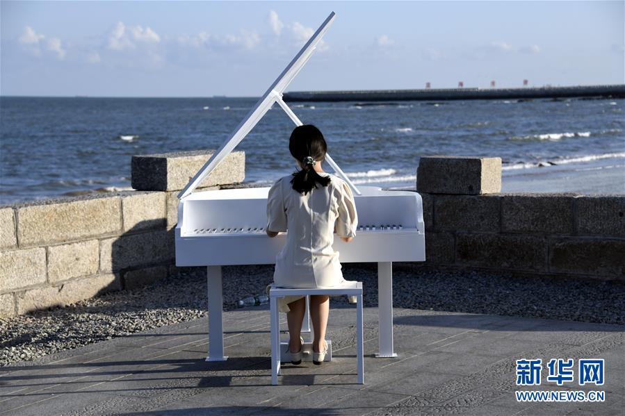 9月26日，一名游客在日照市海洋美学馆面朝大海弹奏钢琴。 当日，山东日照市天气晴好，阳光明媚，不少市民和游客来到海边游玩。 新华社记者 范长国 摄