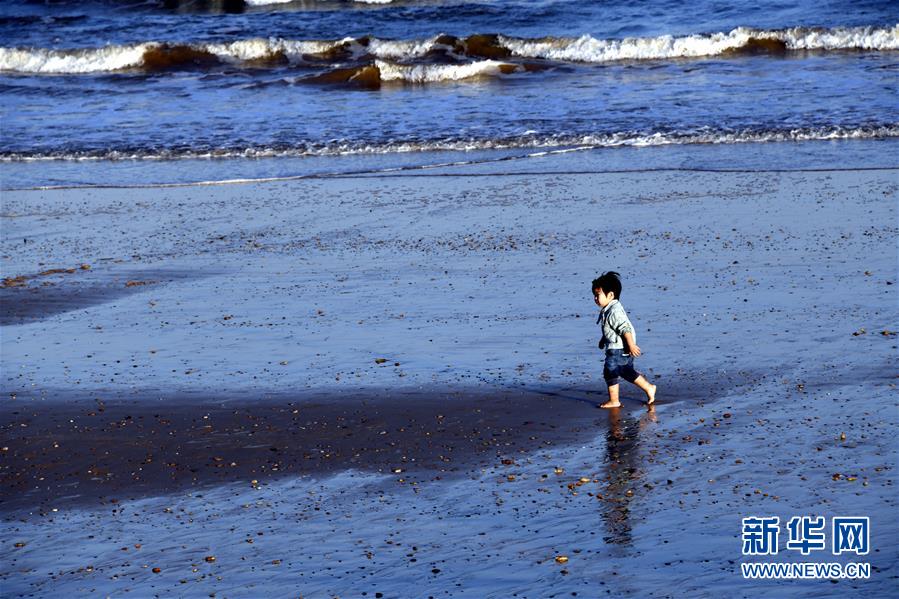 9月26日，一名小朋友在日照市山海天旅游度假区海滨玩耍。 当日，山东日照市天气晴好，阳光明媚，不少市民和游客来到海边游玩。 新华社记者 范长国 摄