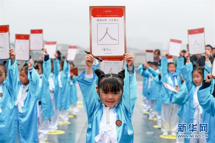 9月28日，小学生们手举自己在“开笔礼”上写的“人”字。新华社记者 欧东衢 摄