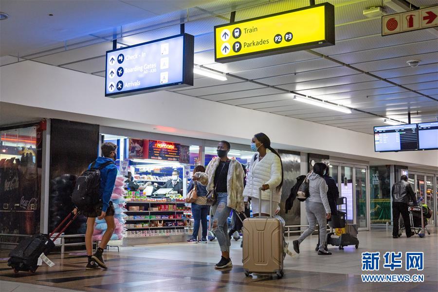 10月1日，在南非约翰内斯堡坦博国际机场，人们戴口罩从店面旁走过。新华社发（耶希尔摄）