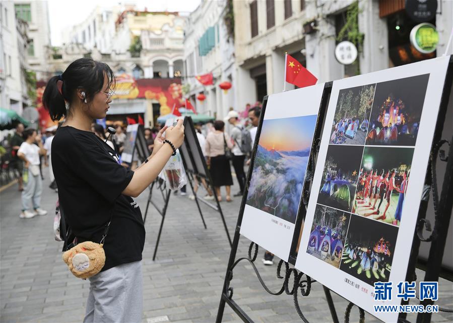 10月2日，游客在海口骑楼老街观看摄影展。 当日是国庆假期第二天，许多游客来到海口骑楼老街参观游览。 新华社记者 张丽芸 摄