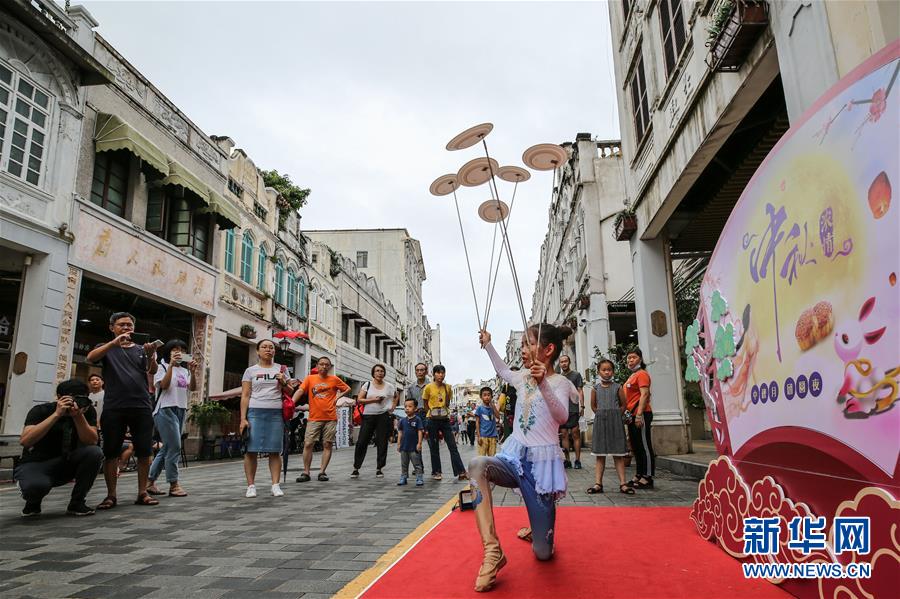 10月2日，游客在海口骑楼老街观看杂技表演。 当日是国庆假期第二天，许多游客来到海口骑楼老街参观游览。 新华社记者 张丽芸 摄