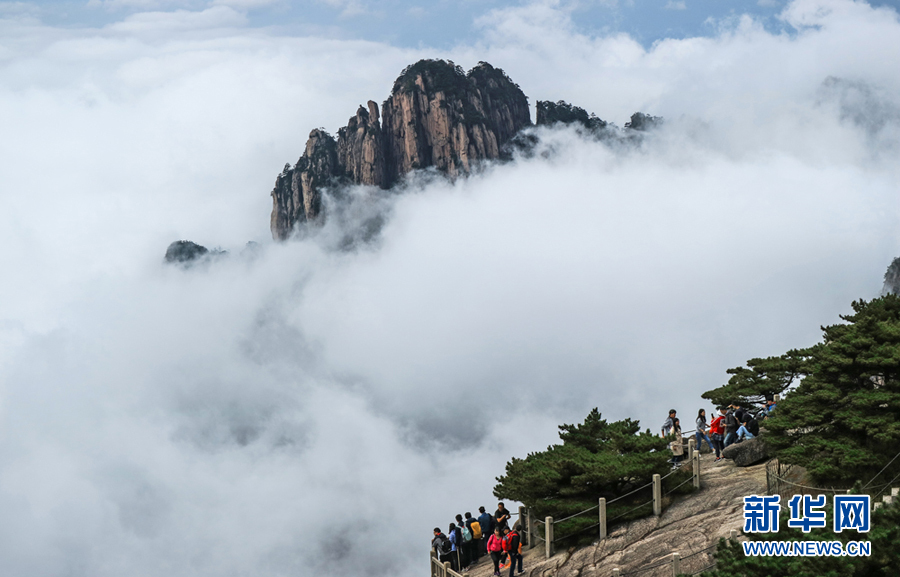  10月5日，安徽黄山风景区雨后出现大面积云海景观，山峰怪石在翻腾的云海中时隐时现，宛如仙境，吸引游客驻足观赏。 10月5日，安徽黄山风景区雨后出现大面积云海景观，山峰怪石在翻腾的云海中时隐时现，宛如仙境，吸引游客驻足观赏。新华网发（李金刚 摄）