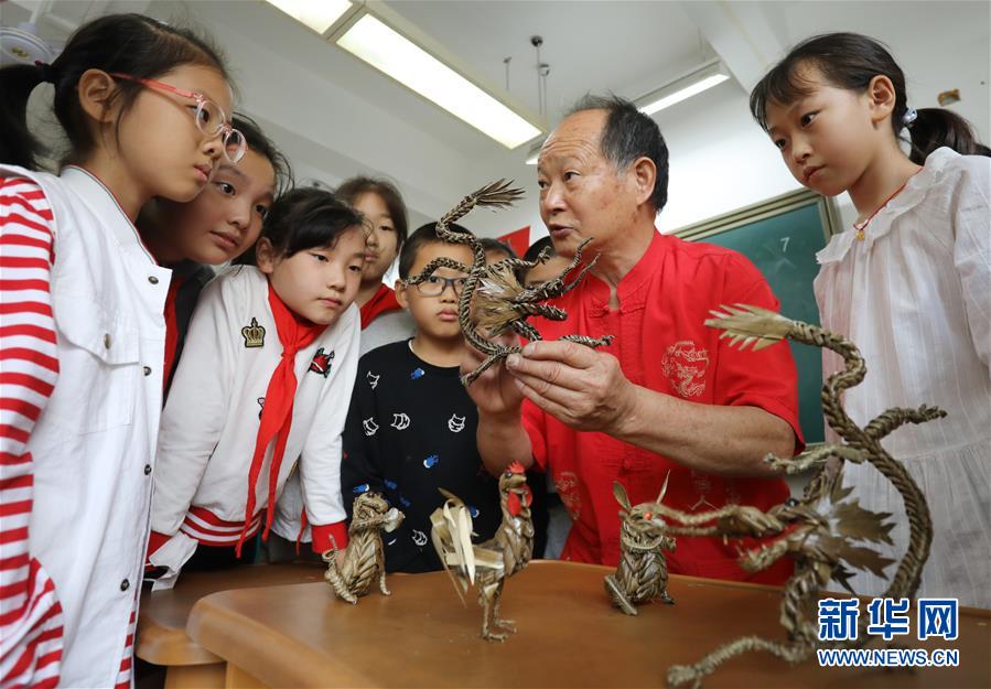 10月9日，民间艺人在苏州工业园区星海小学向孩子们讲解棕编技艺。 当日，江苏苏州工业园区星海小学开展“传统文化手工制作体验“活动，孩子们在当地手工艺人的指导下，学习剪纸、棕编等手工技艺，感受传统文化。 新华社发（杭兴微 摄）