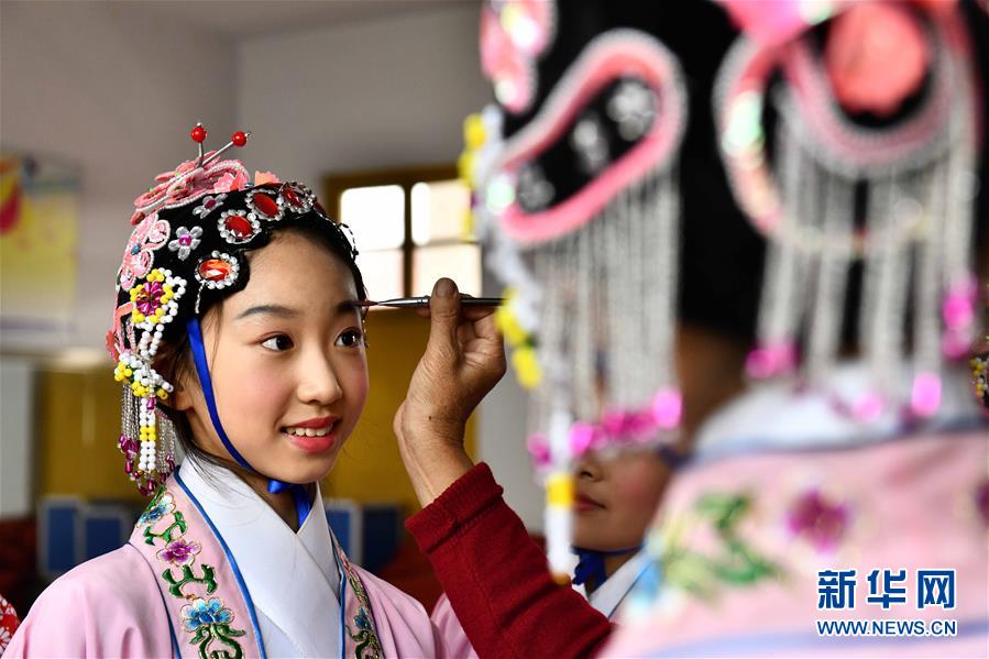 10月28日，在枣庄市台儿庄区西关小学，文艺志愿者给小学员描眉。为传承中华优秀传统文化，近年来山东省枣庄市台儿庄区依托新时代文明实践中心三级网络，组织文艺志愿者作为校外辅导员，推动京剧、豫剧、柳琴戏、黄梅戏等优秀传统戏剧进校园，让小学员们体验戏曲文化魅力。新华社记者 郭绪雷 摄