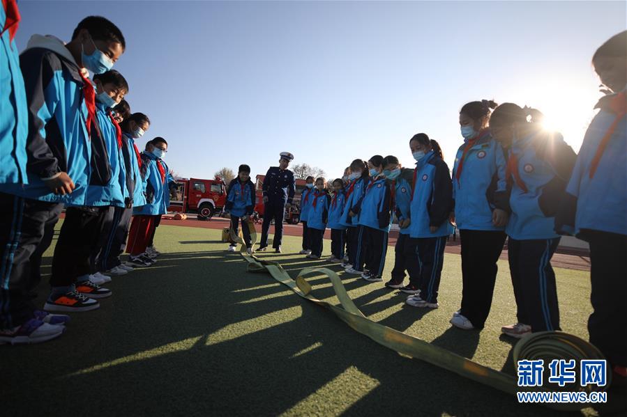 11月3日，在承德市双桥区普宁小学，学生在消防救援人员指导下体验使用消防器材。 当日，河北省承德市双桥区消防救援大队与普宁小学联合开展消防进校园安全互动体验教育活动。学生们通过体验救生设备、安全使用消防器材等，在互动活动中学习消防知识，提升自救能力，迎接“119消防宣传日”。 新华社发（刘环宇 摄）