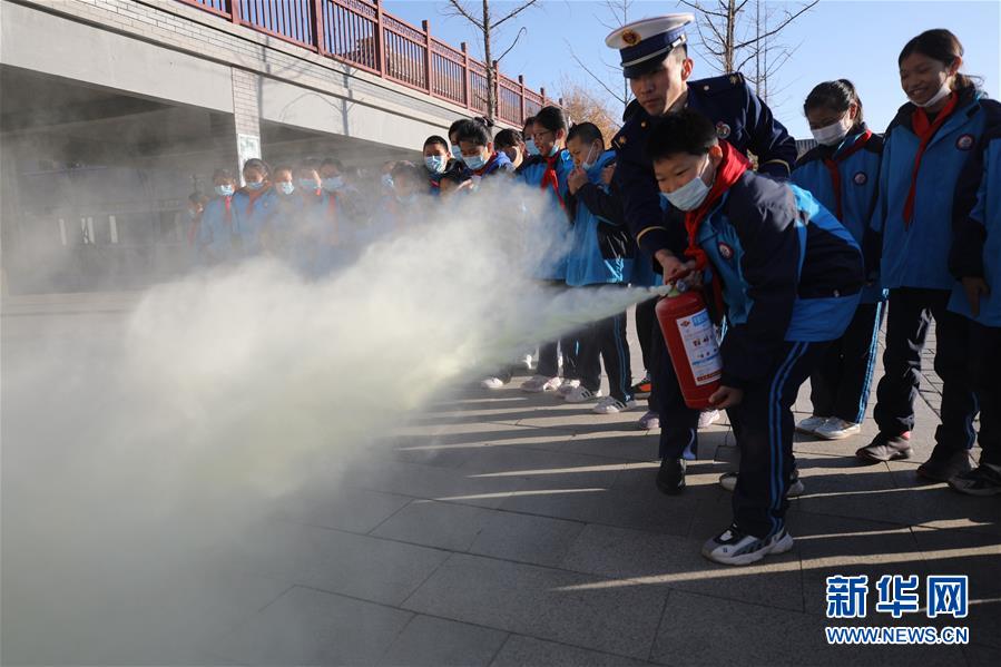 11月3日，在承德市双桥区普宁小学，学生在消防救援人员指导下学习使用灭火器。 当日，河北省承德市双桥区消防救援大队与普宁小学联合开展消防进校园安全互动体验教育活动。学生们通过体验救生设备、安全使用消防器材等，在互动活动中学习消防知识，提升自救能力，迎接“119消防宣传日”。 新华社发（刘环宇 摄）