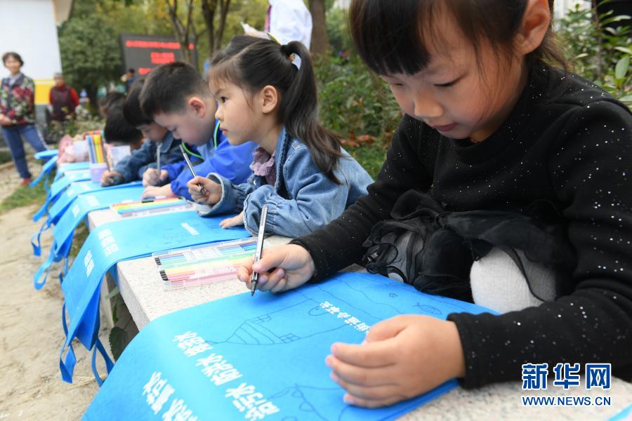 11月16日，小学生在藤桥港河道沿岸绘制公益宣传袋，准备分发给当地居民。2013年起，浙江湖州吴兴区环渚街道开始对辖区内污染较严重的藤桥港河道进行整治，强化落实河长制，加大水生植物种植率，并通过手机APP及时上报巡河问题，使河道水环境面貌和水质获得明显改善。新华社记者 翁忻旸 摄