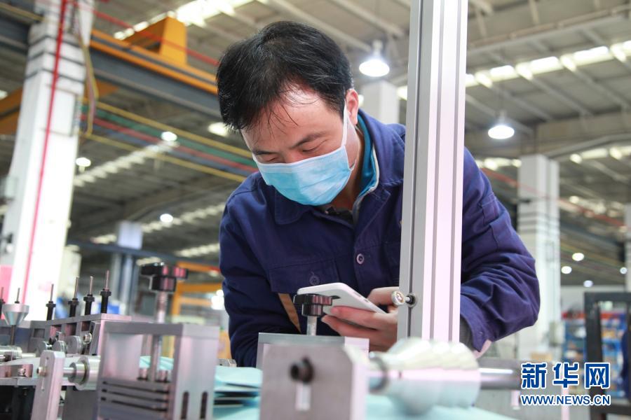 2月21日，机械工程师吴科龙在国机智能口罩机生产车间调试口罩机。新华社发