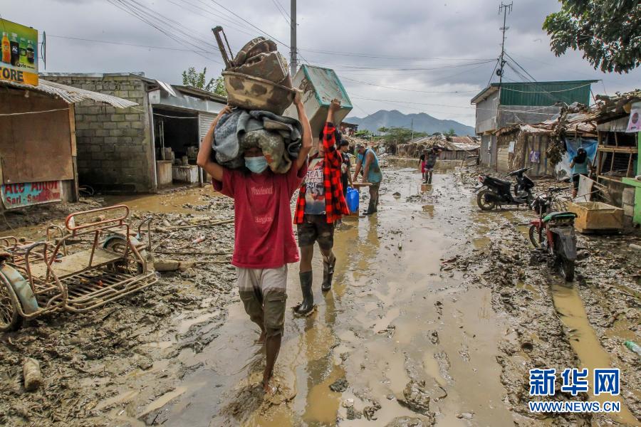 11月16日，在菲律宾黎刹省，居民在泥水中运送物品。根据菲律宾国家减灾管理委员会发布的灾情通报，过境菲律宾的台风“环高”在该国造成的死亡人数已升至67人。新华社发（乌马利摄）