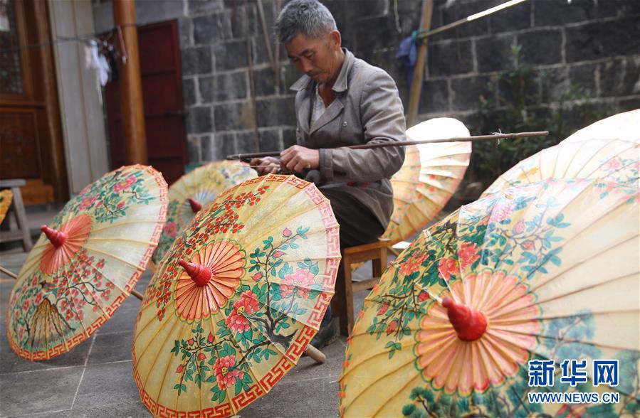 11月17日，荥阳村的纸伞艺人在制作油纸伞。 云南省腾冲市固东镇荥阳村有着上百年制作油纸伞的历史，但机制雨伞的出现和其价格优势，让手工制作的油纸伞市场越来越小。近年来，随着当地旅游业的兴起，样式别致、图案精美的油纸伞作为工艺品受到游客青睐，传承百年的油纸伞焕发了新的生机。 新华社发（梁志强 摄）